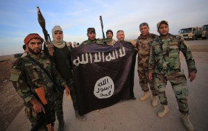 Iraqi Shi'ite fighters pose with an Islamic State flag which they pulled down on the front line in Jalawla, Diyala province, November 23, 2014. Iraqi forces said on Sunday they retook two towns north of Baghdad from Islamic State fighters, driving them from strongholds they had held for months and clearing a main road from the capital to Iran. Picture taken November 23, 2014. REUTERS/Stringer (IRAQ - Tags: CIVIL UNREST POLITICS CONFLICT MILITARY TPX IMAGES OF THE DAY) - RTR4FAVG